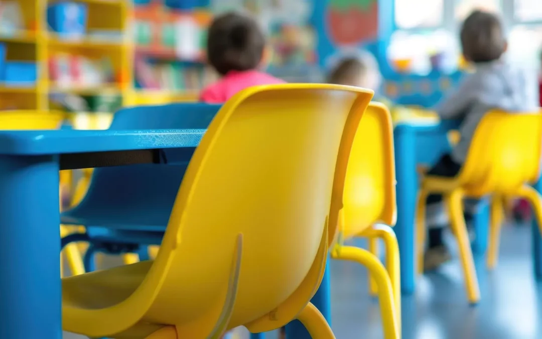 two empty seats in the foreground with four preschool students sitting in seats at desks in the background.