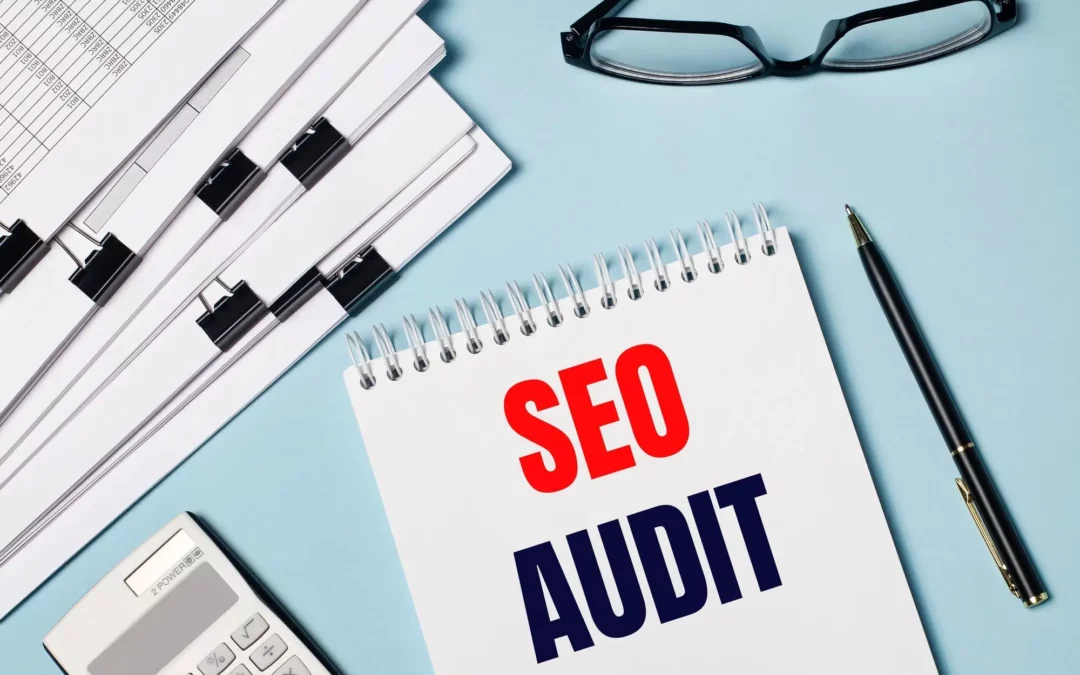 paperwork on top left with glasses next to it and a notepad with seo audit written on it.